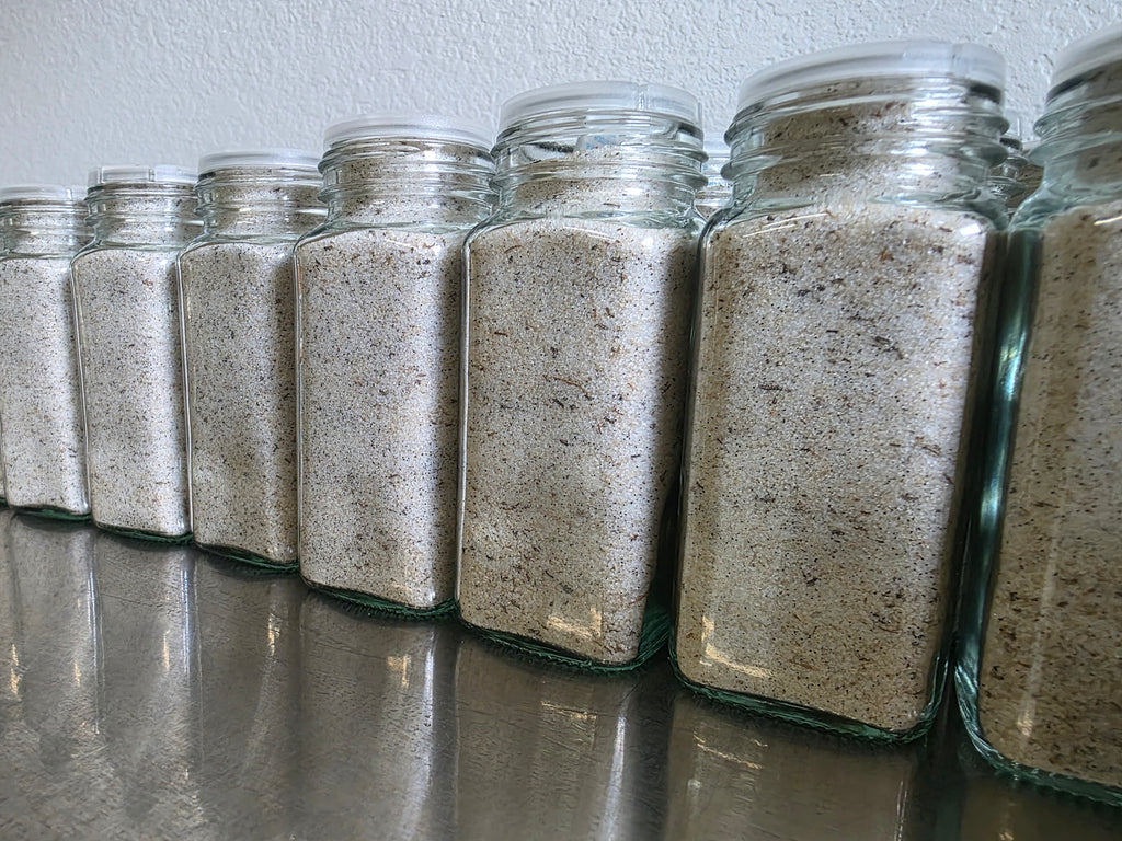 "Close-up of Krazy Sweet Vanilla Bean Finishing Sugar jars with silver lids on a dark marble countertop — small-batch GO TEXAN certified sugar by Plum Krazy Creations"