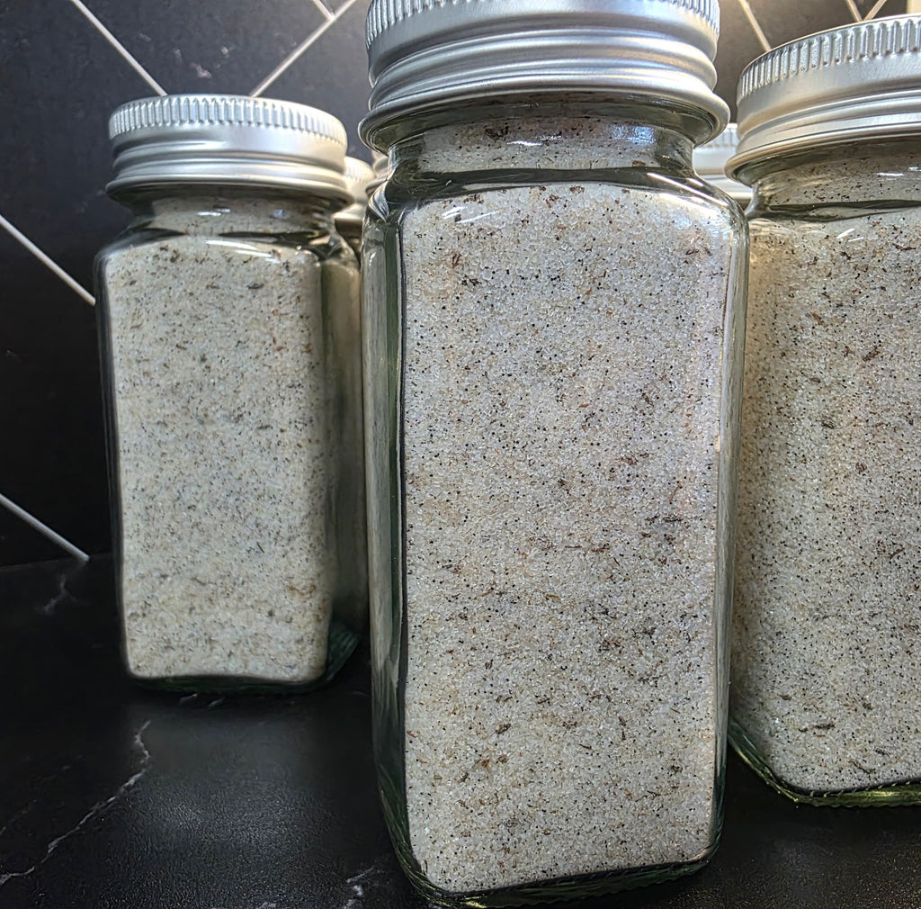 "Multiple jars of Krazy Sweet Vanilla Bean Finishing Sugar by Plum Krazy Creations lined up on a stainless steel surface"