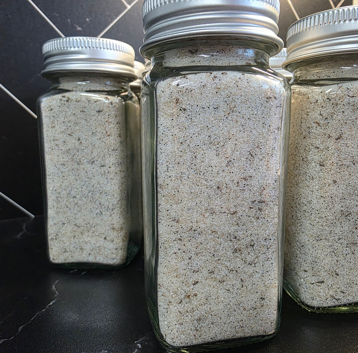 "Multiple jars of Krazy Sweet Vanilla Bean Finishing Sugar by Plum Krazy Creations lined up on a stainless steel surface"